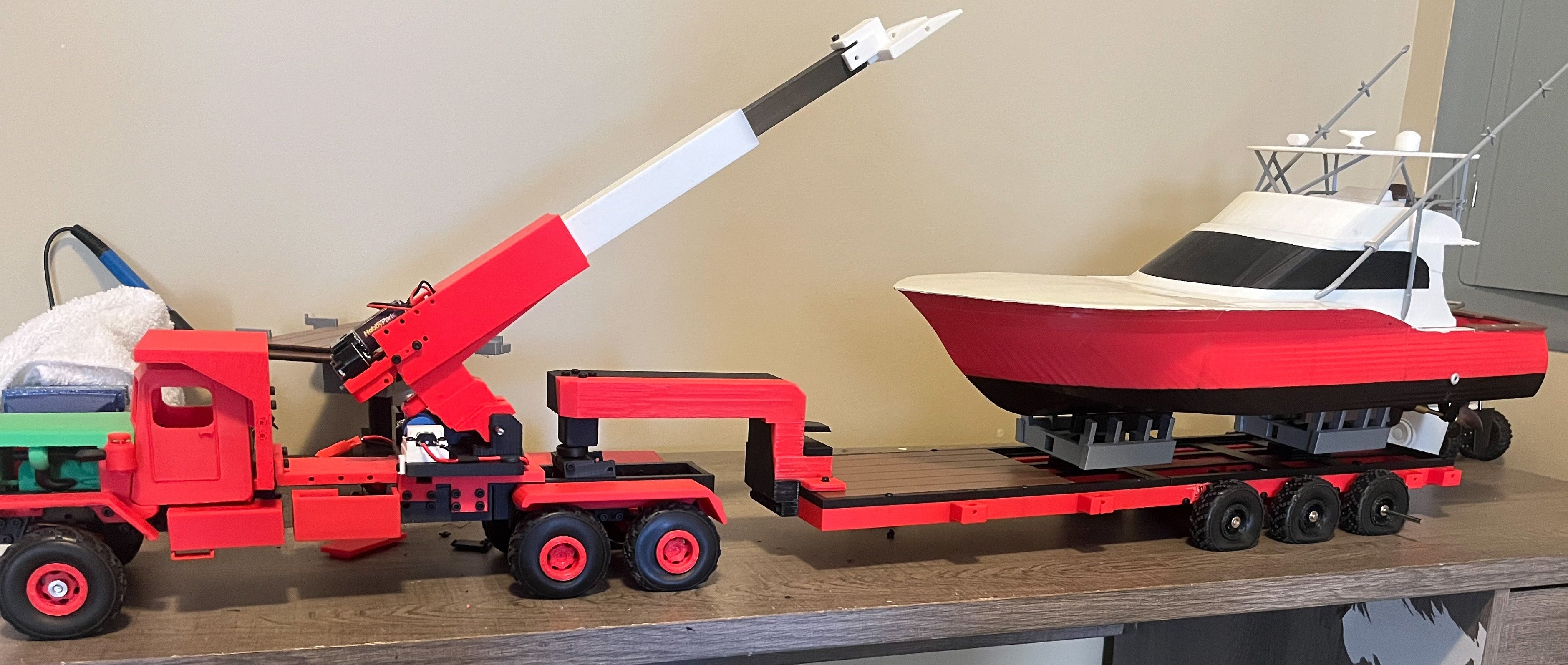Model truck with crane and boat on trailer on a wooden surface